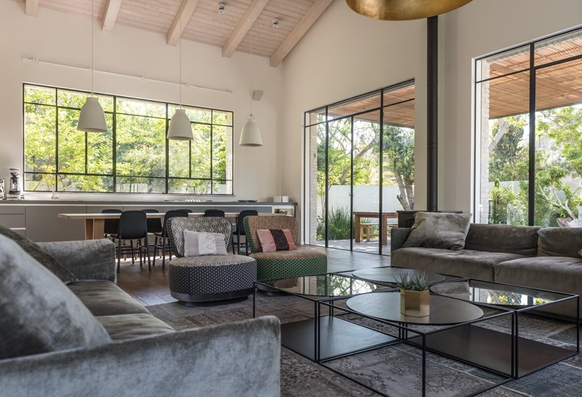 חומריות טבעית: תקרת עץ משופעת, ריצוף פרקט אלון מגוון, ופרופיל בלגי בפתחים הרבים שעוטפים אותו ומייצרים קשר הדוק עם החוץ. צילום: גלעד רדט