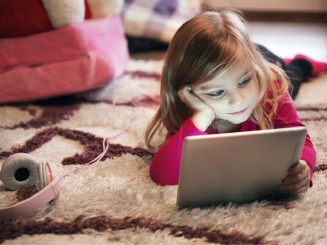 ילדה משועממת על השטיח עם טאבלט. אילוסטרציה: freepik